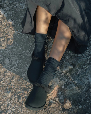 woman with black vegan slippers and black skirt
