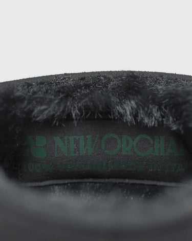 Close-up on boots of a dark gray plush item branding on a light gray background