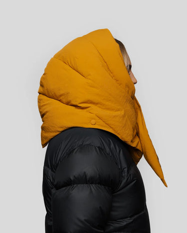 Amber yellow vegan puffer hood with pointed tip, made from recycled materials, worn over black jacket. - The New Orchard - Amber Yellow