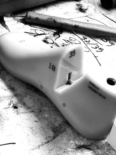 White shoe fill component with markings on a dirty workbench