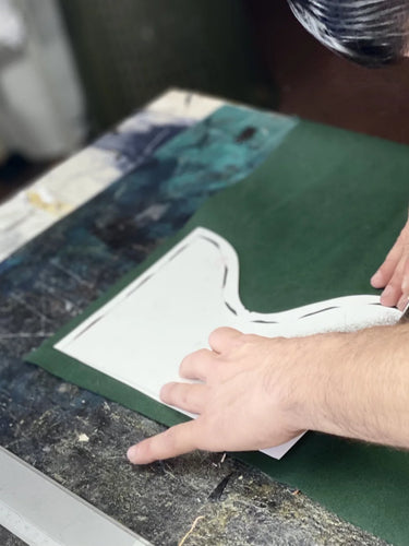 Person cutting a green vegan leather with knife.