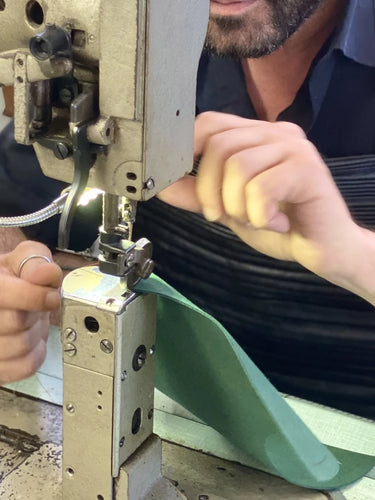 Person using a sewing machine to work on a green vegan fabric item.