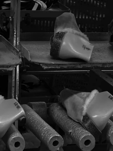 Row of plastic shoe tool components on a conveyor belt in a factory setting