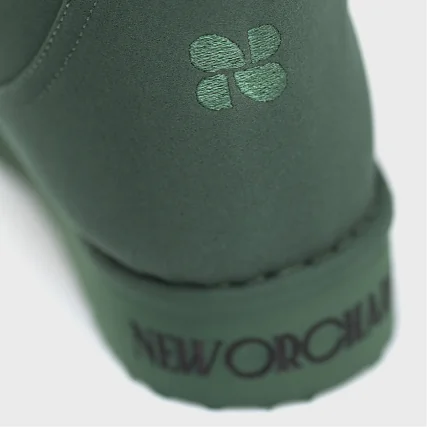 Close-up of a green shoe with a brand logo on a white background