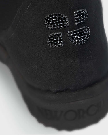Close-up of a black vegan shoe with a brand logo on a white background